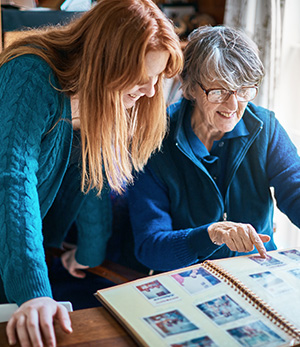 Elderly lady and daughter looking at old family photos