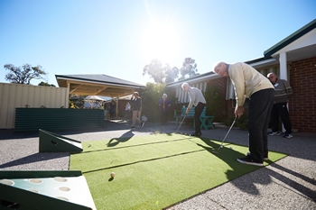 Two elderly gentlemen living with dementia playing golf outside at Mary Chester House Respite Centre