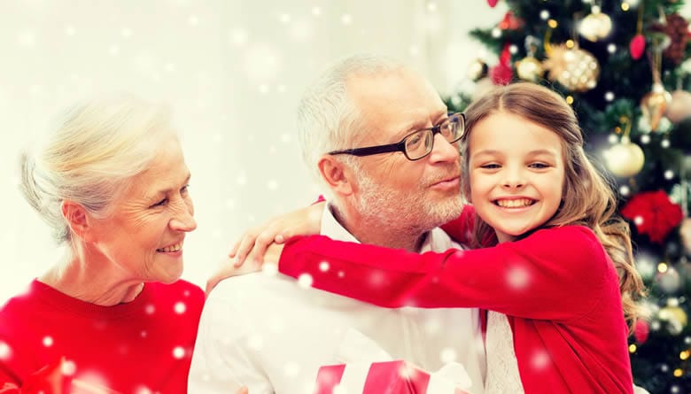 An elderly man living with dementia kissing his granddaughter on the cheek at Christmas time