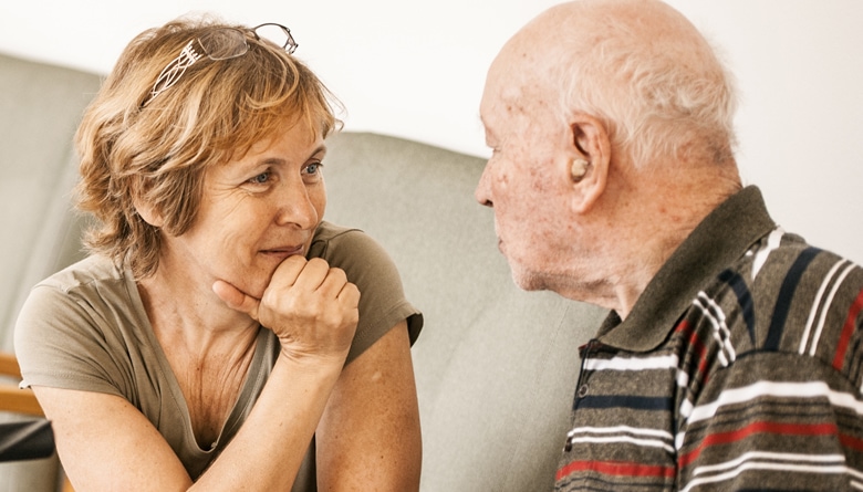 A middle-aged woman having a conversation with her elderly father about dementia