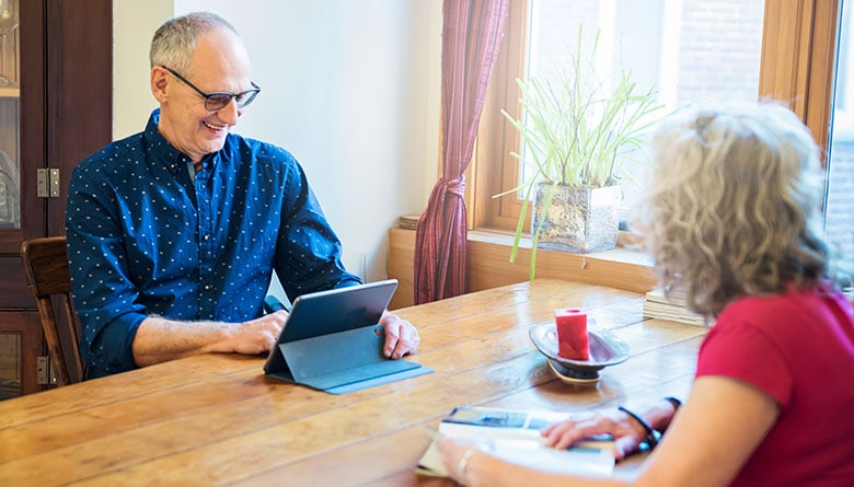 Elderly man looking at an iPad while female reads a magazine