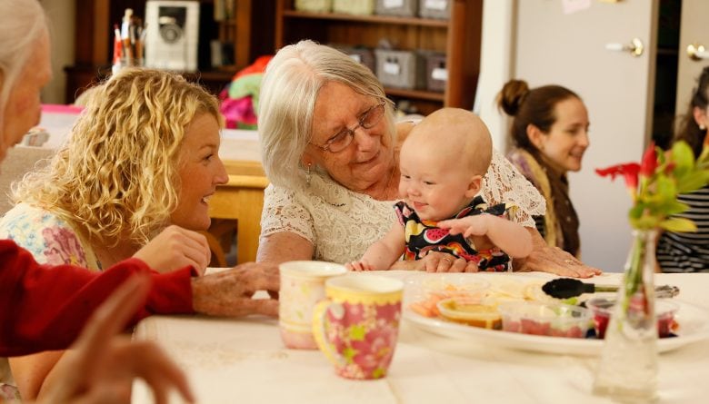 Senior lady holding a baby and remaining socially active