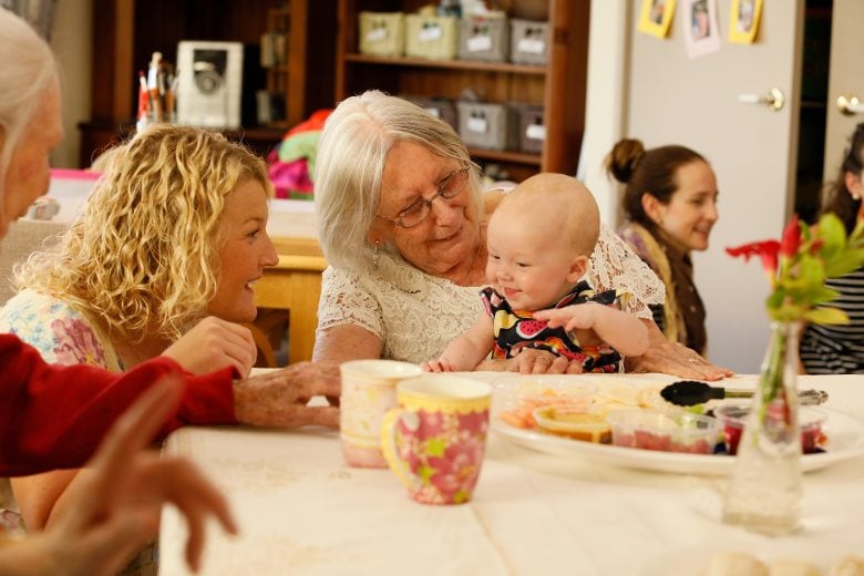 Senior lady holding a baby and remaining socially active