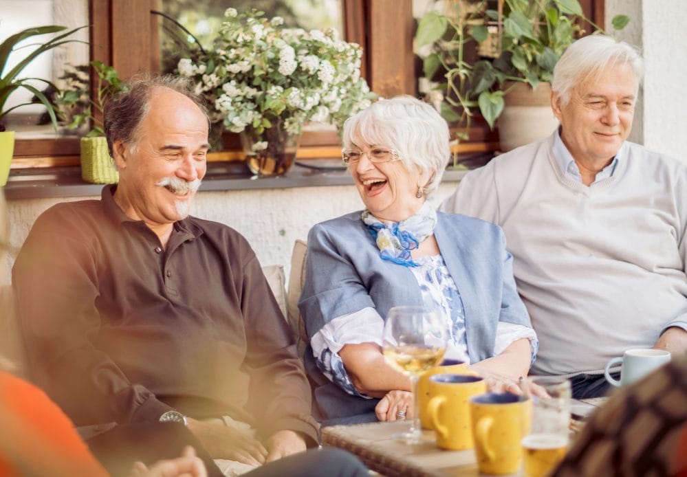 Group Of Mature Friends Enjoying Outdoor Meal In Backyard