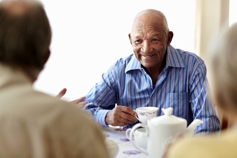 Happy senior man having breakfast with friends