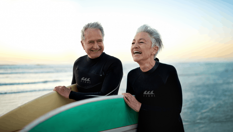 Senior couple at the beach with their surfboards