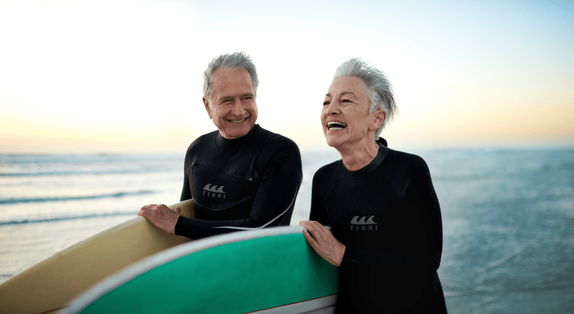 Senior couple at the beach with their surfboards