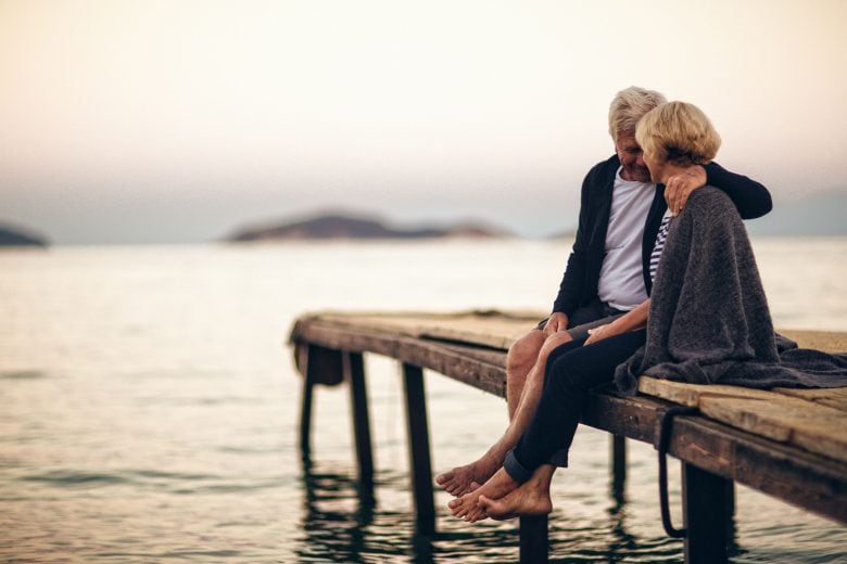 Senior couple sitting together on a jetty.