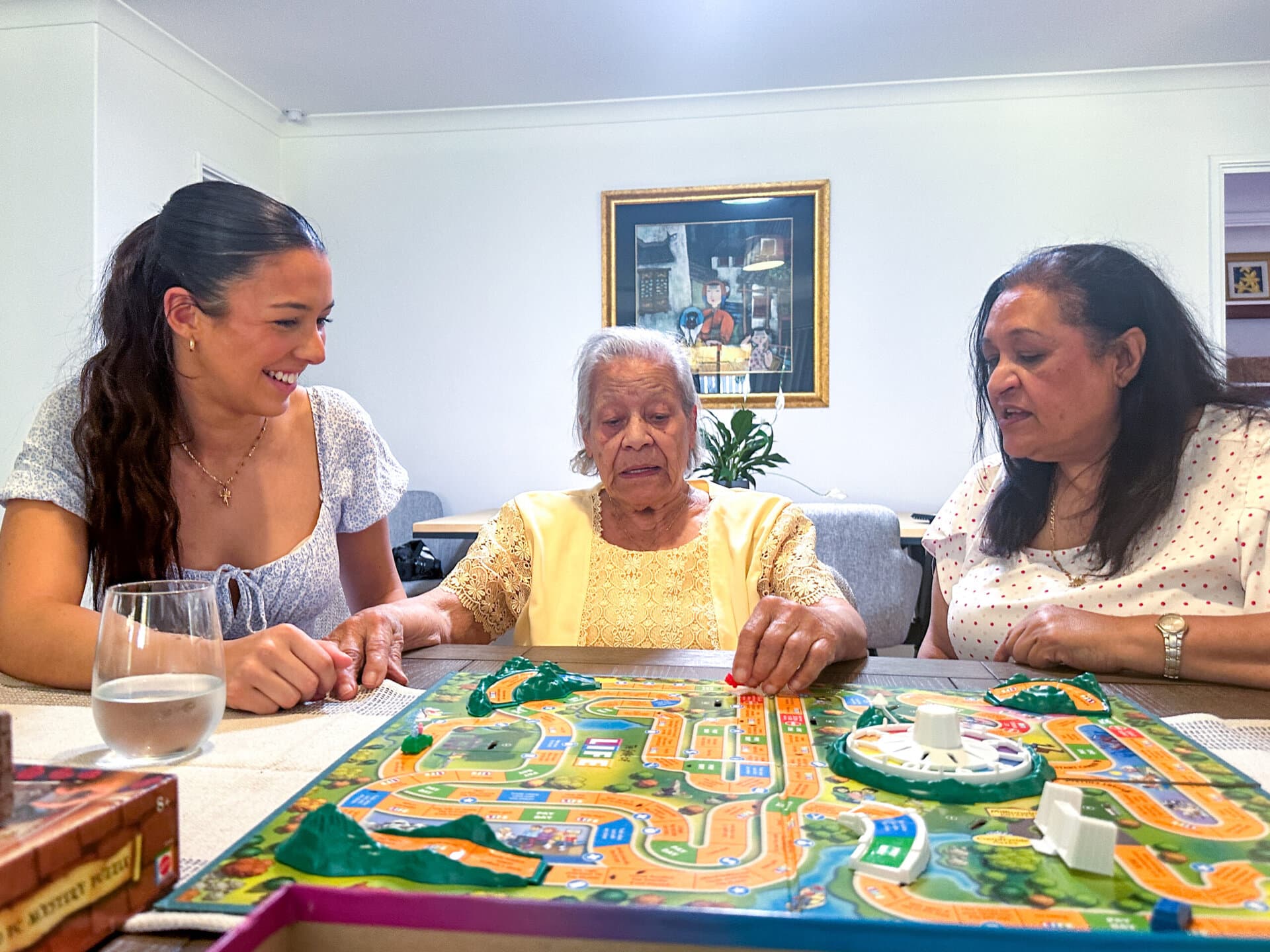 Three women play a board game at a table.